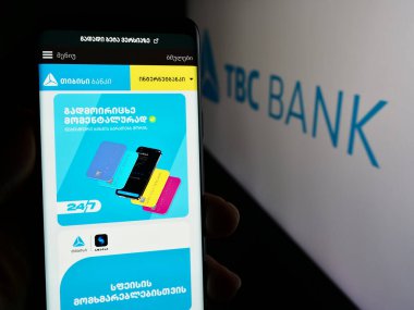 Stuttgart, Almanya - 05-29-2024: Gürcü finans hizmetleri şirketi TBC Bank Group plc 'nin logolu web sayfası ile akıllı telefon sahibi kişi. Telefon ekranının merkezine odaklan.
