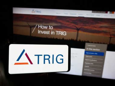 Stuttgart, Almanya - 05-29-2024: İnternet sayfası önünde Yenilenebilir Altyapı Grubu Ltd. (TRIG) adlı şirketin logosuna sahip kişi. Telefon ekranına odaklan.
