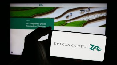 Stuttgart, Almanya - 05-30-2024: Vietnamlı Dragon Capital Group Limited şirketinin logosuna sahip akıllı telefon sahibi kişi web sitesinin önünde. Telefon ekranına odaklan.