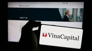Stuttgart, Almanya - 05-30-2024: İnternet sayfasının önünde Vietnamlı yatırım şirketi VinaCapital 'in logosuna sahip cep telefonu sahibi kişi. Telefon ekranına odaklan.