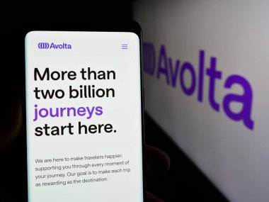 Stuttgart, Almanya - 05-31-2024: İsviçreli seyahat perakende şirketi Avolta AG 'nin web sayfası ile cep telefonu sahibi kişi iş logosu önünde. Telefon ekranının merkezine odaklan.