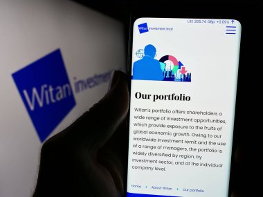 Stuttgart, Almanya - 05-31-2024: İngiliz Witan Investment Trust plc şirketinin web sitesi ile logo önünde cep telefonu bulunduran kişi. Telefon ekranının merkezine odaklan.