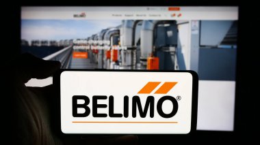 Stuttgart, Almanya - 05-31-2024: İsviçreli kontrol sistemleri şirketi Belimo Holding AG 'nin logosuyla cep telefonu sahibi kişi iş sayfası önünde. Telefon ekranına odaklan.