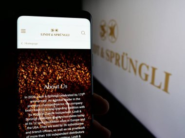 Stuttgart, Almanya - 05-31-2024: Cep telefonunda İsviçreli firma Chocoladefabriken Lindt ve Sprungli AG 'nin logosu olan kişi web sayfasının önünde. Telefon ekranına odaklan.