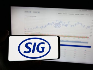Stuttgart, Almanya - 05-31-2024: İsviçreli ambalaj şirketi SIG Group AG 'nin logosuna sahip cep telefonu sahibi kişi iş sayfasının önünde. Telefon ekranına odaklan.