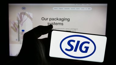 Stuttgart, Almanya - 05-31-2024: İsviçreli ambalaj şirketi SIG Group AG 'nin logosuna sahip akıllı telefon sahibi kişi web sitesi önünde. Telefon ekranına odaklan.