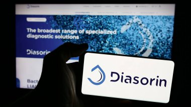Stuttgart, Almanya - 06-01-2024: İtalyan biyoteknoloji şirketi DiaSorin S.P.A. 'nın logosuna sahip akıllı telefon sahibi kişi web sitesi önünde. Telefon ekranına odaklan.