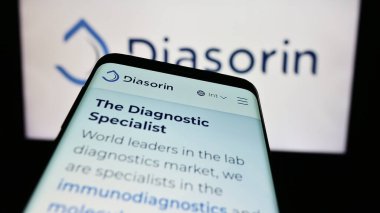 Stuttgart, Germany - 06-01-2024: Smartphone with website of Italian biotechnology company DiaSorin S.p.A. in front of business logo. Focus on top-left of phone display. clipart