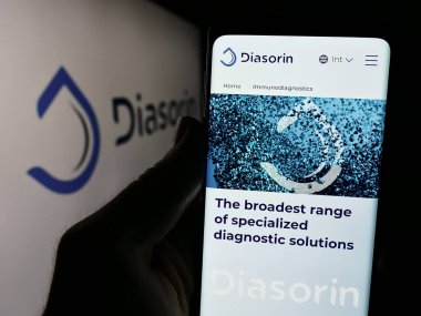 Stuttgart, Almanya - 06-01-2024: İtalyan biyoteknoloji şirketi DiaSorin S.P.A. 'nın web sayfası ile logo önünde cep telefonu tutan kişi. Telefon ekranının merkezine odaklan.