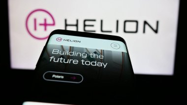 Stuttgart, Almanya - 06-03-2024: Amerikan füzyon enerji şirketi Helion Energy Inc. 'in web sitesi ile birlikte iş logosu önünde cep telefonu. Telefon ekranının sol üst kısmına odaklan.