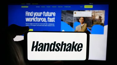 Stuttgart, Almanya - 06-03-2024: İnternet sayfası önünde Amerikan yazılım şirketi Stryder Corp. (Handshake) logosu olan cep telefonu sahibi kişi. Telefon ekranına odaklan.