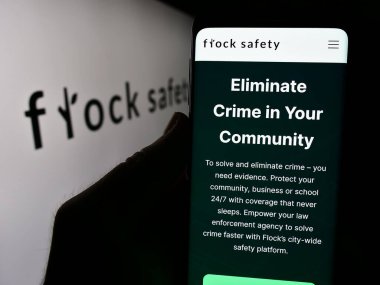 Stuttgart, Almanya - 06-03-2024: ABD 'li video izleme şirketi Flock Safety' nin web sayfası olan akıllı telefonu iş logosu önünde tutan kişi. Telefon ekranının merkezine odaklan.