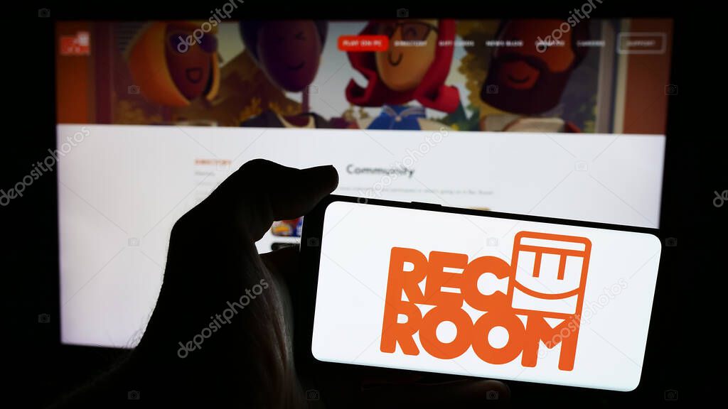 Stuttgart, Germany - 06-01-2024: Person holding mobile phone with logo of American video games company Rec Room Inc. in front of business web page. Focus on phone display.