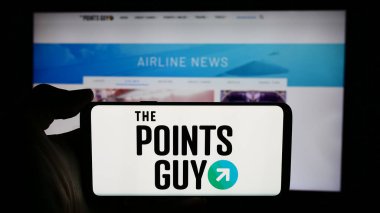 Stuttgart, Almanya - 06-03-2024: ABD 'li seyahat medya şirketi The Points Guy' ın logosuyla cep telefonu tutan kişi iş sayfasının önünde. Telefon ekranına odaklan.
