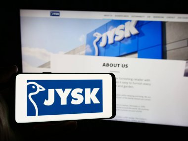 Stuttgart, Almanya - 06-03-2024: İnternet sitesinin önünde Danimarkalı ev eşyaları perakende şirketi Jysk AS 'nin logosuna sahip kişi. Telefon ekranına odaklan.