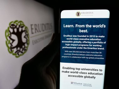 Stuttgart, Almanya - 03-06-2024: Singapur şirketi Eruditus Executive Education 'ın logo önündeki web sayfası ile cep telefonu tutan kişi. Telefon ekranının merkezine odaklan.
