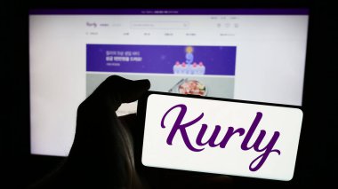 Stuttgart, Almanya - 03-06-2024: Güney Koreli market e-ticaret şirketi Kurly 'nin logosunu taşıyan cep telefonu sahibi kişi iş sayfasının önünde. Telefon ekranına odaklan.