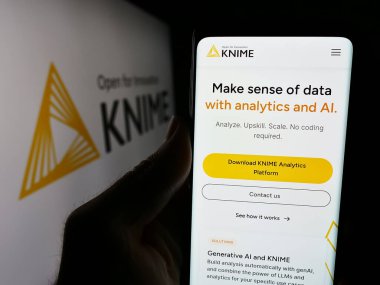 Stuttgart, Almanya - 06-06-2024: Analitik yazılım şirketi KNIME AG 'nin web sayfası ile birlikte iş logosu önünde cep telefonu tutan kişi. Telefon ekranının merkezine odaklan.
