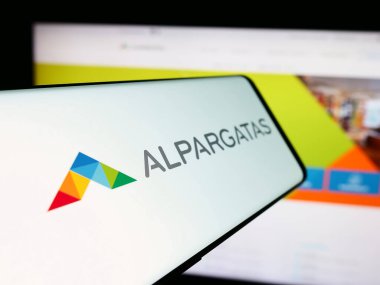 Stuttgart, Almanya - 06-06-2024: Brezilyalı ayakkabı firması Alpargatas SA 'nın logosunu taşıyan cep telefonu. Telefon ekranının merkez soluna odaklan.