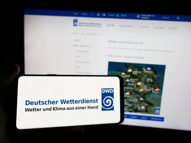 Stuttgart, Almanya - 06-06-2024: İnternet sitesi önünde Alman meteoroloji servisi Deutscher Wetterdienst 'in (DWD) logosuna sahip kişi. Telefon ekranına odaklan.