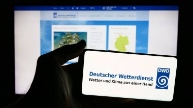 Stuttgart, Almanya - 06-06-2024: İnternet sayfası önünde Alman meteoroloji servisi Deutscher Wetterdienst 'in (DWD) logosuna sahip cep telefonu sahibi kişi. Telefon ekranına odaklan.