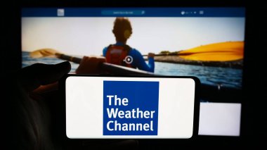 Stuttgart, Almanya - 06-06-2024: Üzerinde ABD 'li ankesörlü televizyon kanalı The Weather Channel' ın (TWC) logosu bulunan cep telefonu sahibi iş sayfası önünde bulunuyor. Telefon ekranına odaklan.