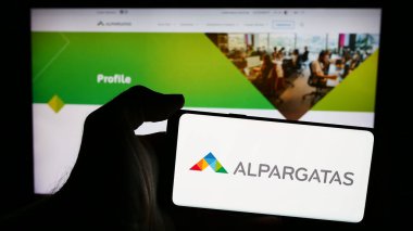 Stuttgart, Almanya - 06-06-2024: Brezilyalı ayakkabı şirketi Alpargatas S.A. 'nın logosuna sahip akıllı telefon sahibi kişi web sitesinin önünde. Telefon ekranına odaklan.