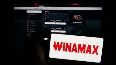 Stuttgart, Germany - 06-06-2024: Person holding smartphone with logo of French sports betting company Winamax SA in front of website. Focus on phone display. clipart