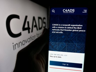 Stuttgart, Almanya - 06-06-2024: Logo önünde İleri Savunma Çalışmaları Merkezi (C4ADS) web sayfası bulunan kişi. Telefon ekranının merkezine odaklan.