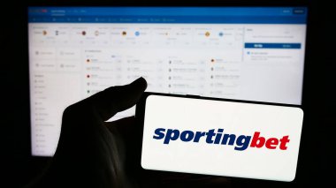 Stuttgart, Almanya - 06-06-2024: İngiliz spor bahisleri şirketi Sportingbet plc 'nin logosuna sahip cep telefonu sahibi kişi iş sayfasının önünde. Telefon ekranına odaklan.