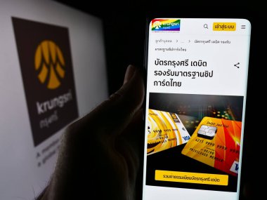 Stuttgart, Almanya - 06-07-2024: Tay 'daki Ayudhya Devlet Bankası Limited (Krungsri) internet sayfası ile akıllı telefon sahibi kişi. Telefon ekranının merkezine odaklan.