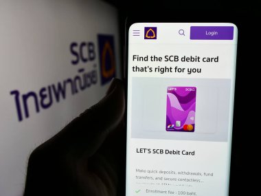 Stuttgart, Almanya - 06-07-2024: The Siam Commercial Bank Public Company Limited 'in (SCB) logolu web sayfası ile akıllı telefon tutan kişi. Telefon ekranının merkezine odaklan.