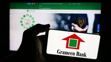 Stuttgart, Almanya - 06-07-2024: Bangladeşli mikrofinans şirketi Grameen Bank 'ın logosunu taşıyan cep telefonu sahibi iş sayfası önünde. Telefon ekranına odaklan.