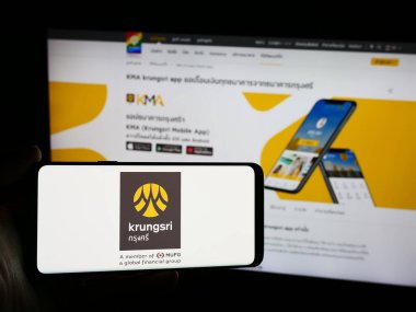 Stuttgart, Almanya - 06-07-2024: İnternet sayfası önünde üzerinde Ayudhya Devlet Bankası logosu bulunan kişi. Telefon ekranına odaklan.