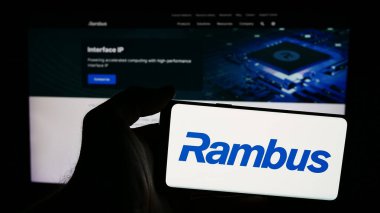 Stuttgart, Almanya - 06-11-2024: İnternet sitesi önünde üzerinde ABD 'li yarı iletken şirket Rambus Inc.' in logosu bulunan kişi. Telefon ekranına odaklan.