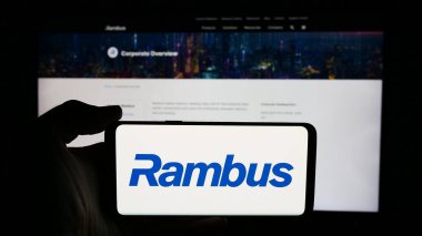 Stuttgart, Almanya - 06-11-2024: ABD 'li yarı iletken şirket Rambus Inc.' in logosuyla cep telefonu sahibi kişi iş sayfası önünde. Telefon ekranına odaklan.