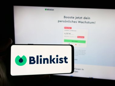 Stuttgart, Almanya - 06-11-2024: İnternet sitesi önünde kitap özetleme şirketi Blink Labs GmbH (Blinkist) logosuna sahip akıllı telefon sahibi kişi. Telefon ekranına odaklan.