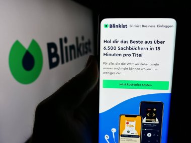 Stuttgart, Almanya - 06-11-2024: Logo önünde Blink Labs GmbH (Blinkist) adlı kitap özetleme şirketinin web sayfası ile akıllı telefon tutan kişi. Telefon ekranının merkezine odaklan.