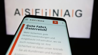 Stuttgart, Almanya - 06-11-2024: Avusturyalı otoyol altyapı şirketi ASFINAG 'ın web sitesi ile birlikte iş logosu önünde cep telefonu. Telefon ekranının sol üst kısmına odaklan.