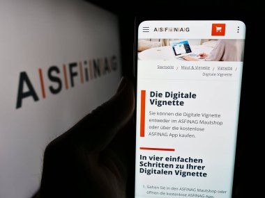 Stuttgart, Almanya - 06-11-2024: Avusturyalı otoyol altyapı şirketi ASFINAG 'ın web sayfası ile logo önünde cep telefonu tutan kişi. Telefon ekranının merkezine odaklan.