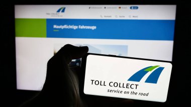 Stuttgart, Almanya - 06-11-2024: Üzerinde Alman otoban gişe sistemi logosu olan cep telefonu sahibi kişi web sayfası önünde Toll Collect GmbH. Telefon ekranına odaklan.