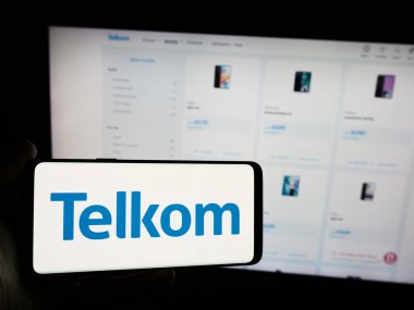 Stuttgart, Almanya - 06-11-2024: Güney Afrikalı Telkom SA SOC Limited şirketinin logosuna sahip cep telefonu sahibi kişi iş sayfası önünde. Telefon ekranına odaklan.