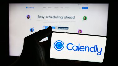 Stuttgart, Almanya - 06-11-2024: ABD 'li iş dünyası yazılım şirketi Calendly LLC' nin logosuna sahip cep telefonu sahibi kişi web sayfası önünde. Telefon ekranına odaklan.
