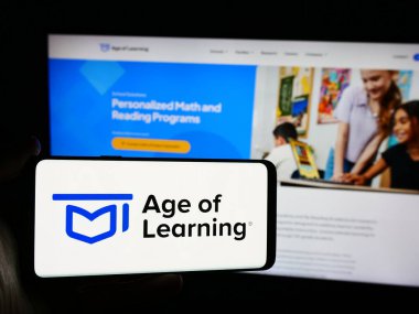 Stuttgart, Almanya - 06-11-2024: Web sayfasının önünde Amerikan online eğitim şirketi Age of Learning Inc. 'in logosu olan cep telefonu sahibi kişi. Telefon ekranına odaklan.