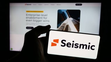 Stuttgart, Almanya - 06-12-2024: İnternet sayfası önünde üzerinde Amerikan satış olanağı sağlayan Sismik Yazılım Şirketi logosu olan cep telefonu sahibi kişi. Telefon ekranına odaklan.
