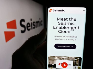 Stuttgart, Almanya - 06-12-2024: ABD 'li satış olanağı sağlayan Sismik Yazılım Şirketi' nin web sayfası ile logonun önünde cep telefonu tutan kişi. Telefon ekranının merkezine odaklan.