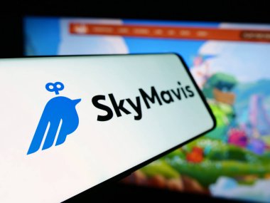 Stuttgart, Germany - 06-12-2024: Cellphone with logo of video games company Sky Mavis Pte. Ltd. in front of business website. Focus on center-left of phone display. clipart