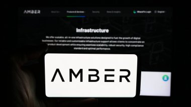 Stuttgart, Almanya - 06-13-2024: Kripto hizmet şirketi Amber Global Limited 'in logosuna sahip cep telefonu sahibi kişi iş sayfasının önünde. Telefon ekranına odaklan.