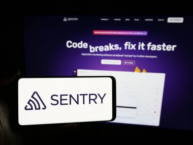Stuttgart, Almanya - 06-13-2024: İnternet sitesi önünde üzerinde ABD 'li Fonksiyonel Yazılım A.Ş. (Sentry) logosu bulunan kişi. Telefon ekranına odaklan.