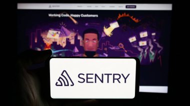 Stuttgart, Germany - 06-13-2024: Person holding cellphone with logo of US company Functional Software Inc. (Sentry) in front of business webpage. Focus on phone display. clipart